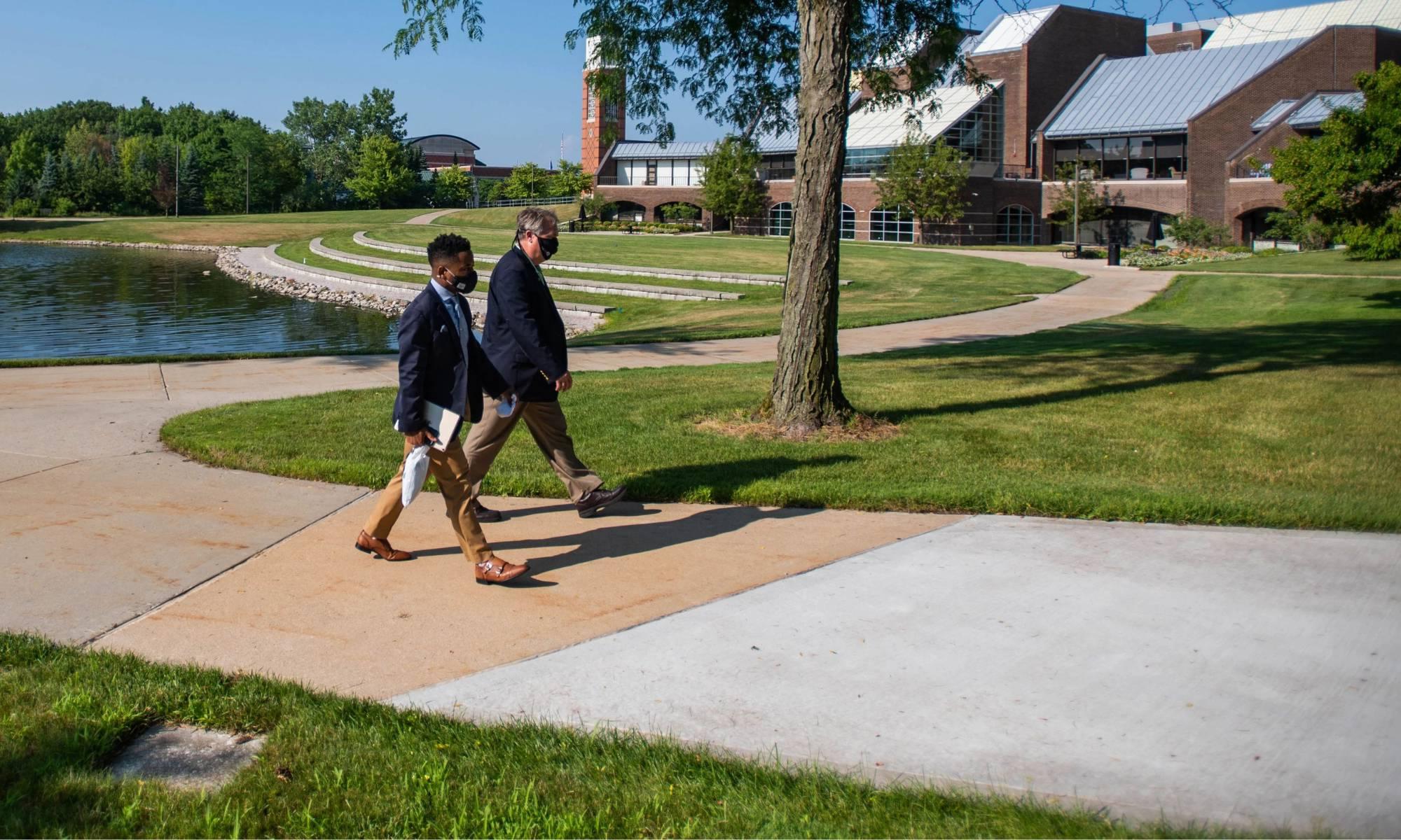 Two people walking by Zumberge Pond on GVSU Allendale Campus